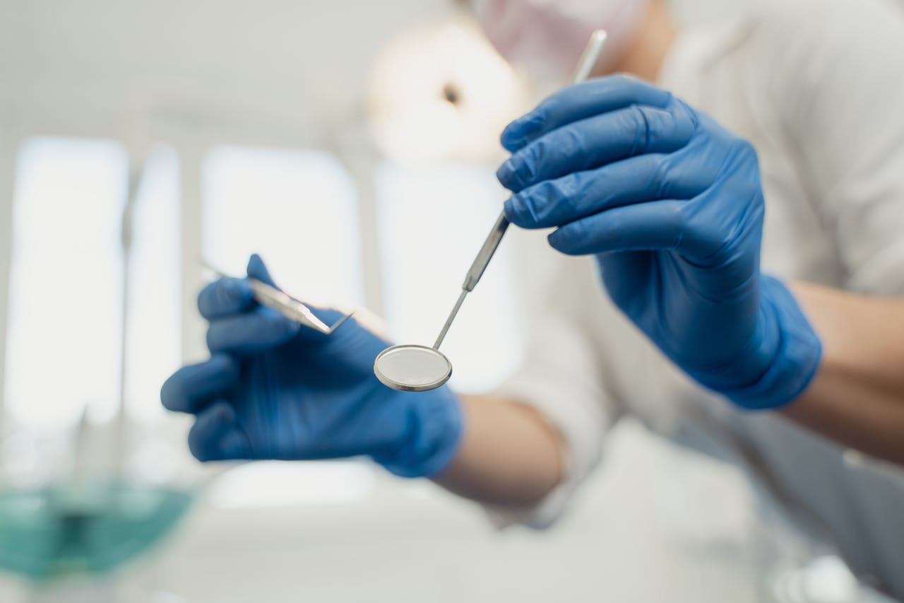 Dentist wearing gloves using dental tools during a procedure.